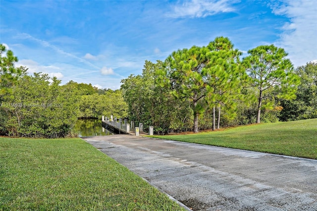 view of community featuring a lawn, concrete driveway, and a dock