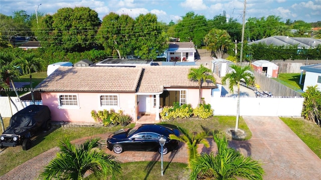 view of front of property with a tile roof, concrete driveway, fence, and stucco siding