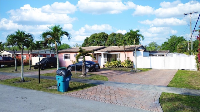 single story home with stucco siding, driveway, fence, and a gate