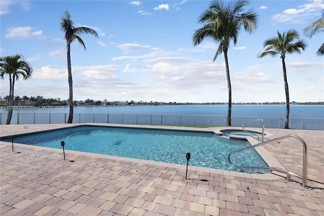 view of pool with a patio, fence, a water view, and a pool with connected hot tub