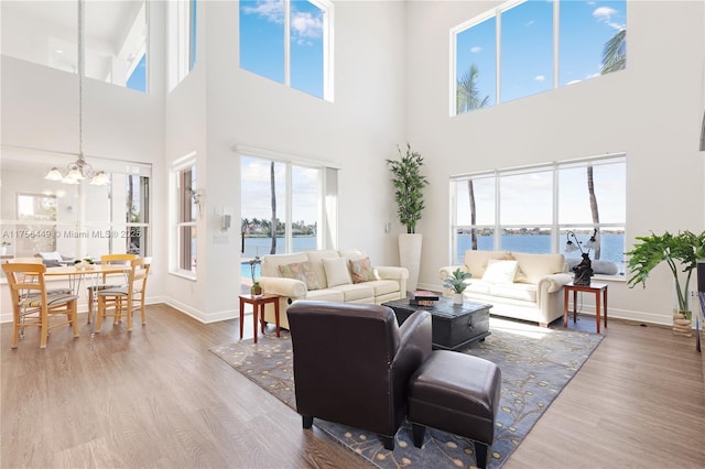 living area with a chandelier, baseboards, wood finished floors, and a water view