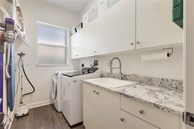 washroom with washing machine and clothes dryer, a sink, baseboards, cabinet space, and dark wood-style flooring