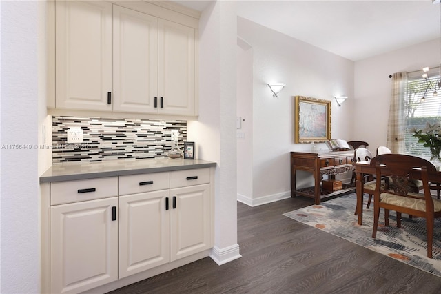 kitchen featuring decorative backsplash, dark wood-type flooring, baseboards, and white cabinetry