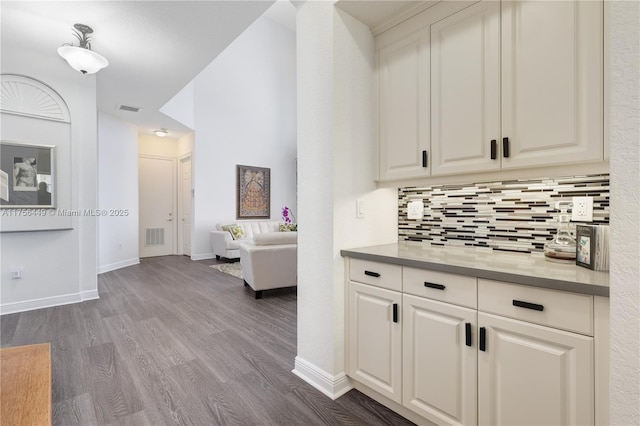 corridor featuring visible vents, baseboards, and dark wood-type flooring