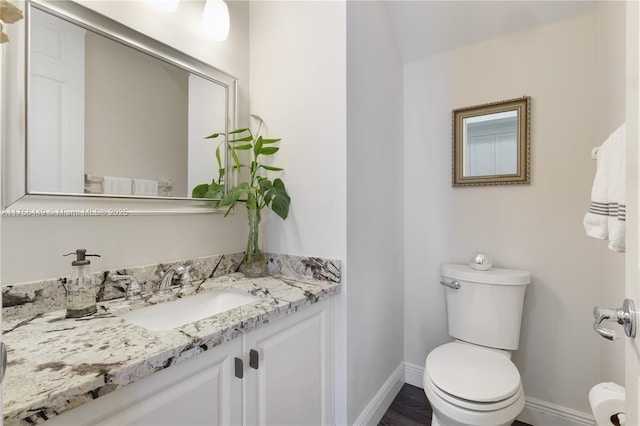 half bathroom with toilet, vanity, and baseboards