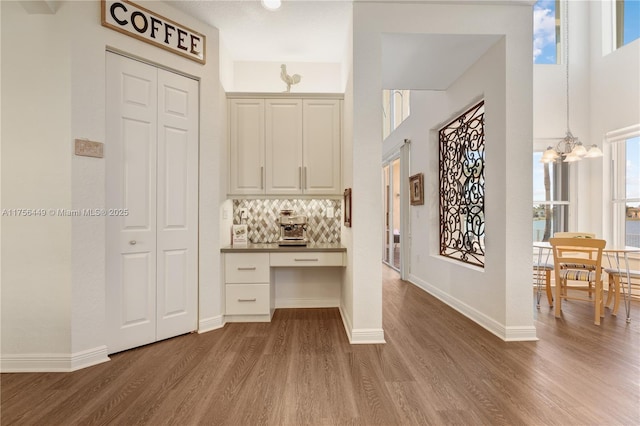 entryway featuring a chandelier, baseboards, wood finished floors, and built in desk