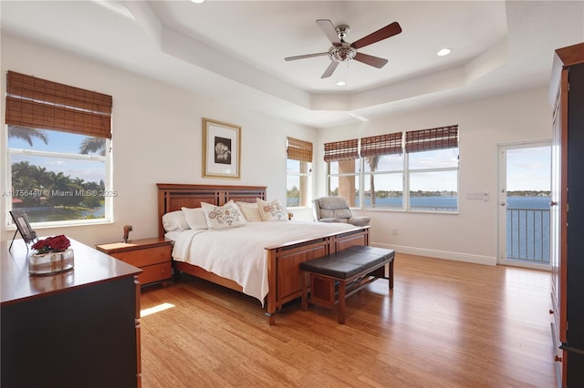 bedroom with baseboards, light wood-style flooring, recessed lighting, ceiling fan, and a raised ceiling