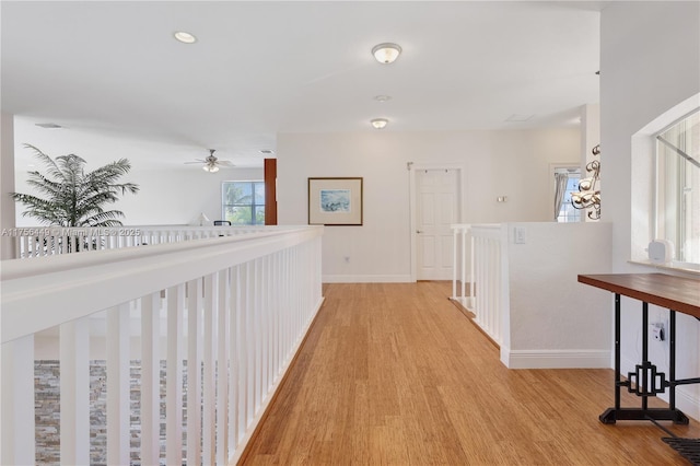 corridor featuring baseboards, light wood-style floors, and an upstairs landing