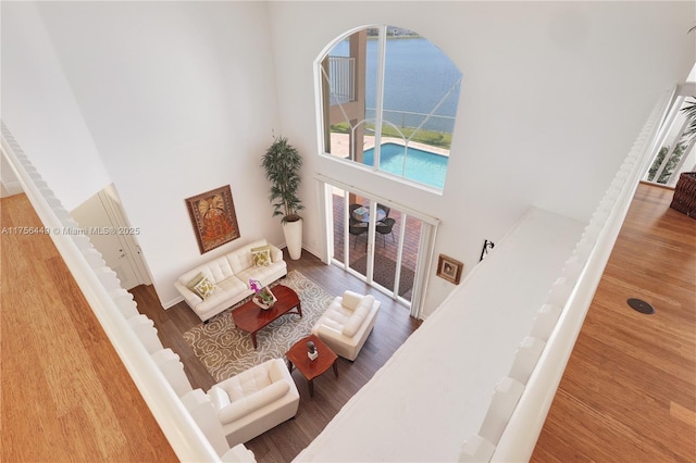 living room with a high ceiling, wood finished floors, and a water view