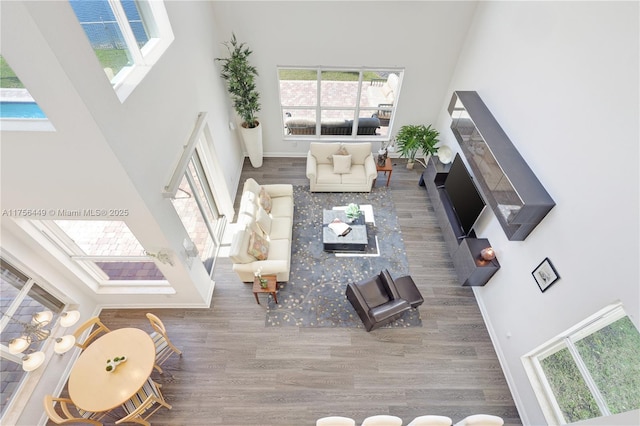 unfurnished living room featuring a high ceiling, wood finished floors, and baseboards