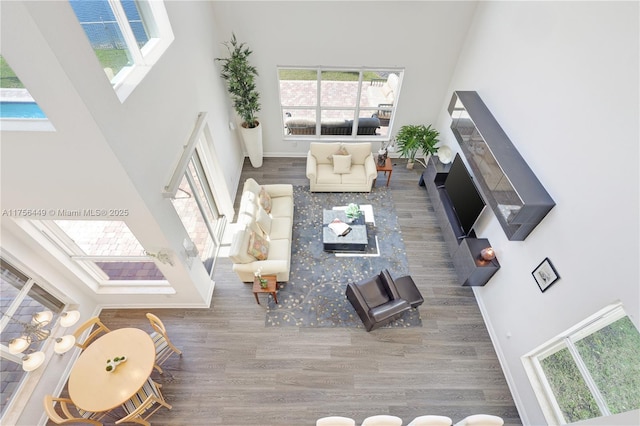 unfurnished living room featuring a fireplace, a high ceiling, wood finished floors, and baseboards