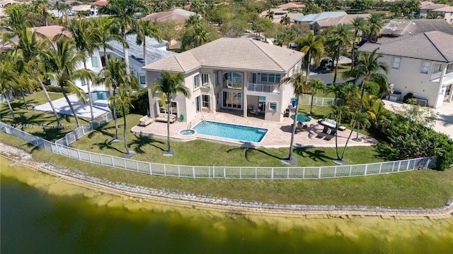 back of property with a water view, a balcony, a fenced backyard, and a patio area