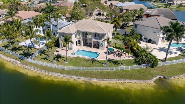 rear view of property featuring a residential view, a balcony, a fenced backyard, and a water view