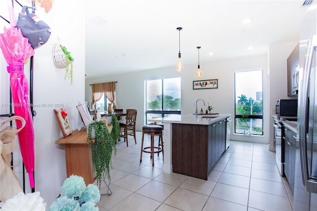 kitchen featuring an island with sink, light countertops, a sink, and light tile patterned flooring