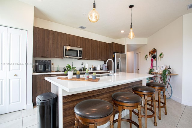 kitchen with a breakfast bar, stainless steel appliances, light countertops, a sink, and light tile patterned flooring