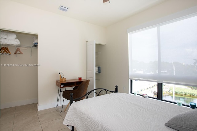 bedroom featuring light tile patterned floors, a water view, visible vents, and baseboards