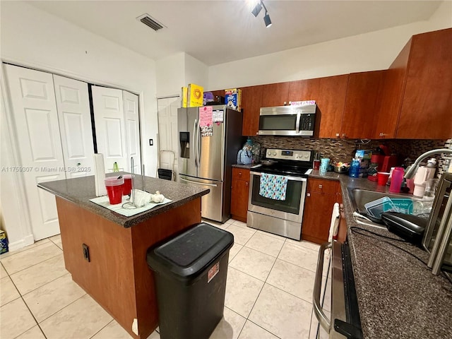 kitchen featuring light tile patterned floors, stainless steel appliances, a sink, visible vents, and dark countertops