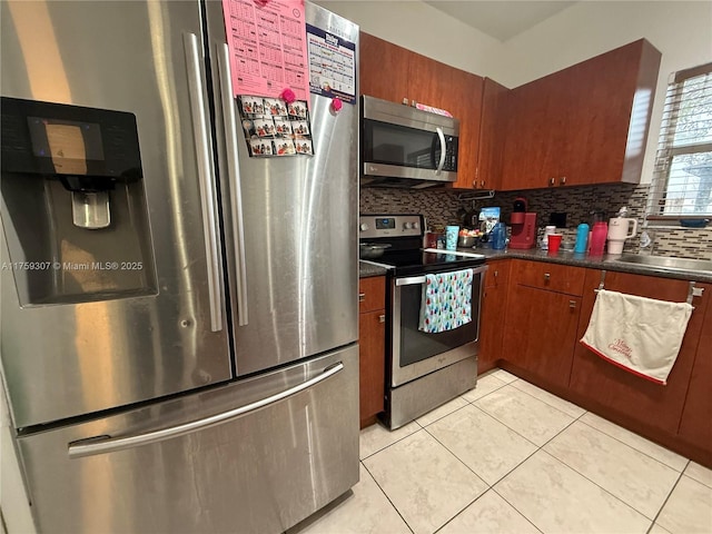 kitchen with dark countertops, a sink, appliances with stainless steel finishes, and backsplash