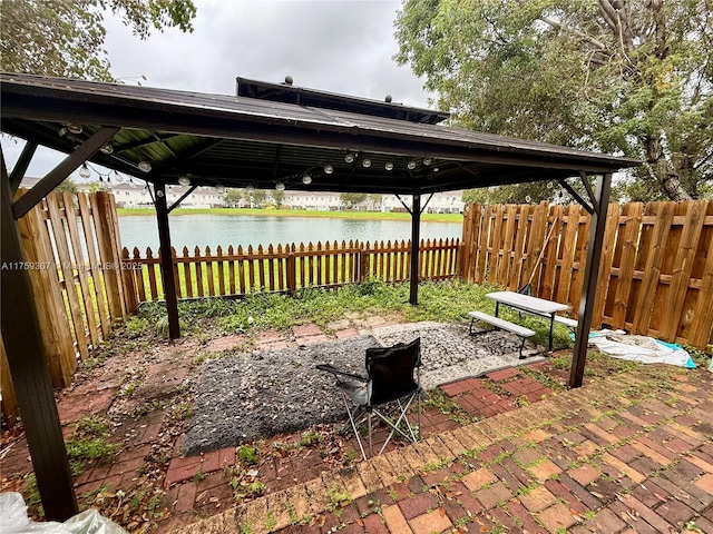 view of patio featuring a water view and fence