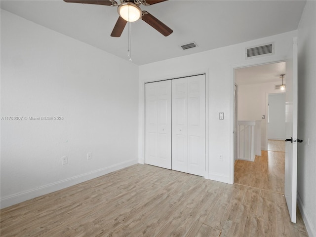 unfurnished bedroom with a closet, light wood finished floors, baseboards, and visible vents