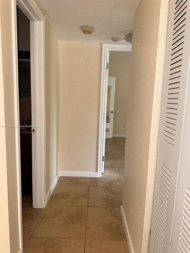 hall featuring tile patterned flooring and baseboards