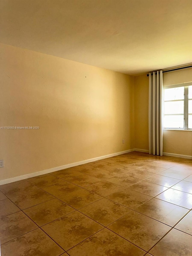 tiled spare room featuring baseboards