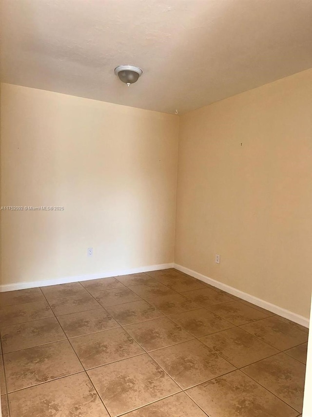 empty room with baseboards and tile patterned floors