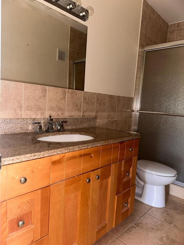 bathroom with a stall shower, vanity, visible vents, and tile walls