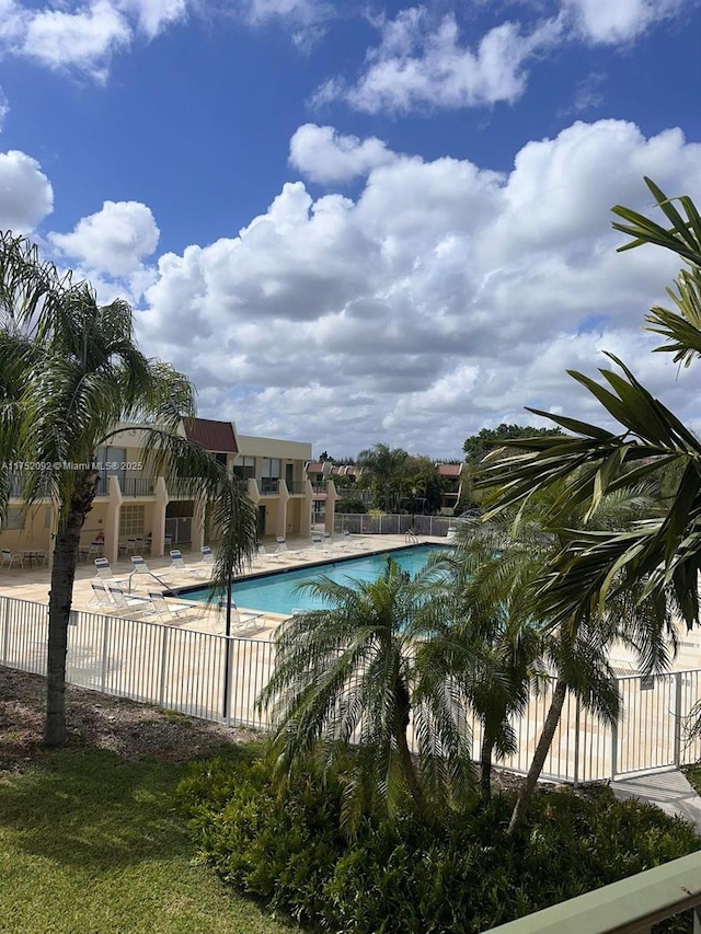 community pool with a patio area and fence