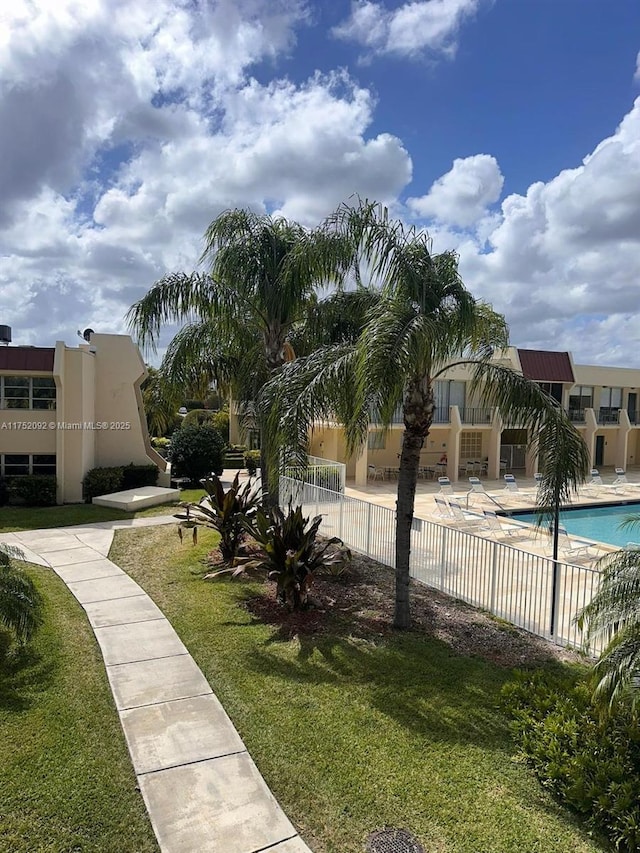 view of property's community featuring a patio area, a swimming pool, fence, and a lawn