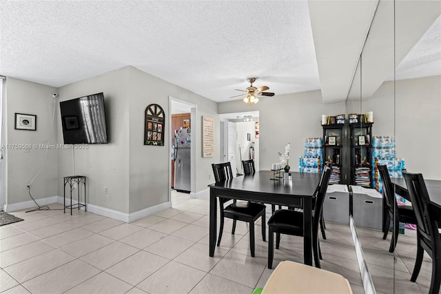 dining room featuring light tile patterned floors, a textured ceiling, baseboards, and a ceiling fan