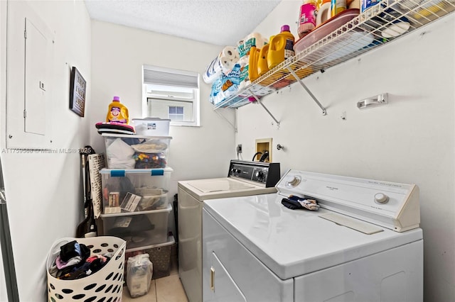 laundry room with laundry area, light tile patterned flooring, a textured ceiling, and separate washer and dryer