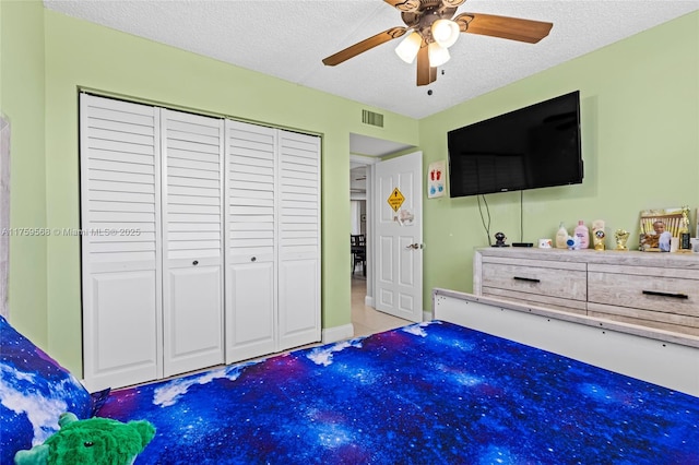 bedroom featuring a closet, visible vents, ceiling fan, and a textured ceiling