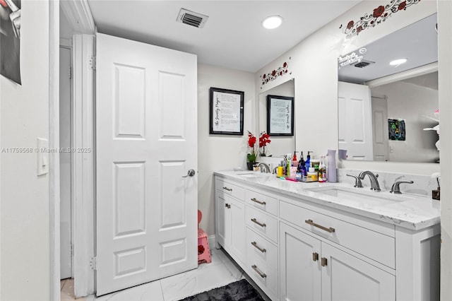 bathroom with marble finish floor, visible vents, a sink, and double vanity