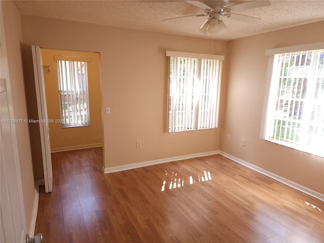 unfurnished room with a ceiling fan, wood finished floors, baseboards, and a textured ceiling