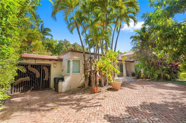 view of front facade featuring a tile roof, a gate, and stucco siding