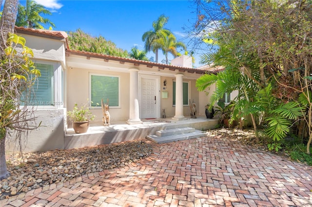 exterior space featuring a porch, a tile roof, and stucco siding