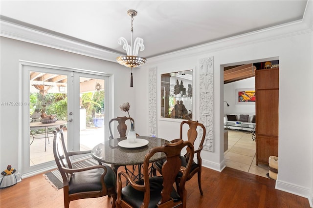 dining area with a chandelier, french doors, crown molding, and wood finished floors