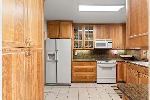 kitchen with white appliances, light tile patterned floors, decorative backsplash, and a sink