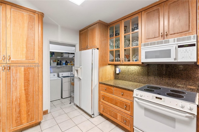 kitchen featuring light tile patterned floors, separate washer and dryer, white appliances, decorative backsplash, and glass insert cabinets