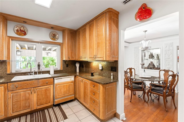 kitchen with french doors, brown cabinets, backsplash, paneled dishwasher, and a sink