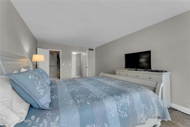 bedroom with baseboards, visible vents, and a walk in closet