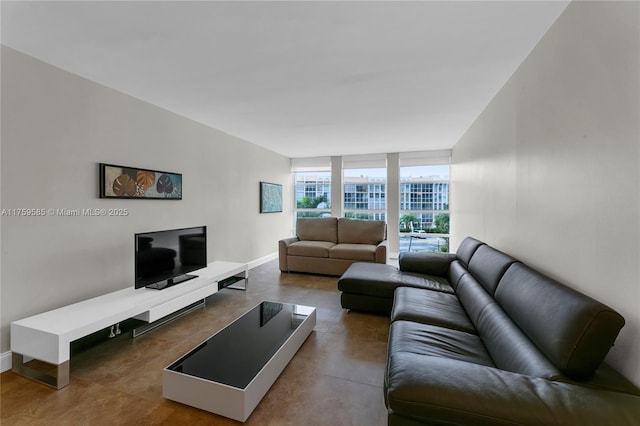 living room featuring baseboards, a wall of windows, and concrete flooring