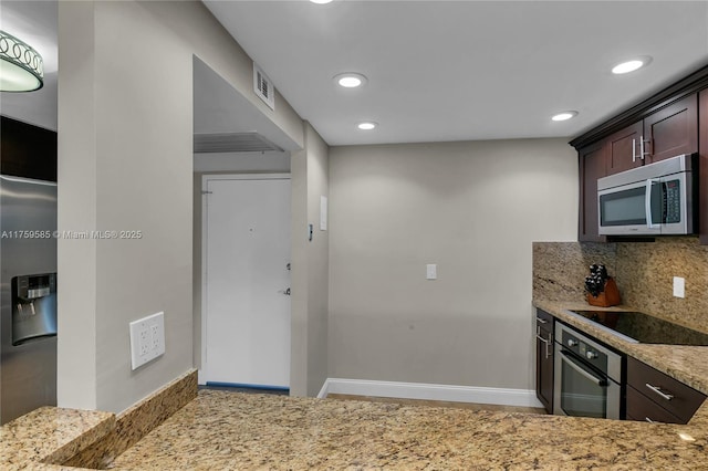 kitchen featuring decorative backsplash, appliances with stainless steel finishes, dark brown cabinetry, light stone countertops, and baseboards