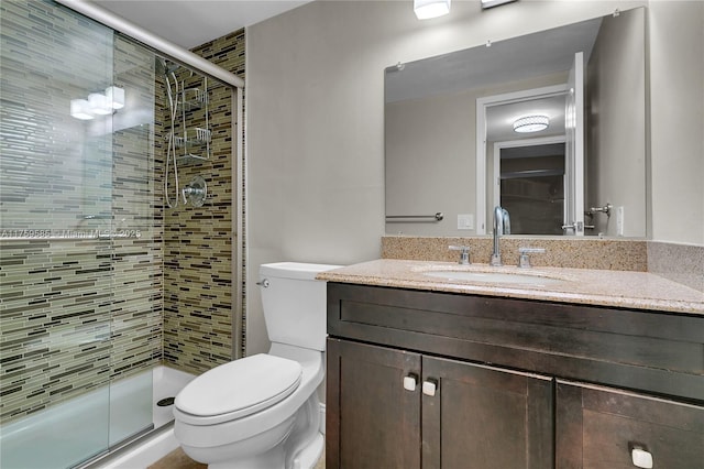 bathroom with vanity, a shower stall, and toilet