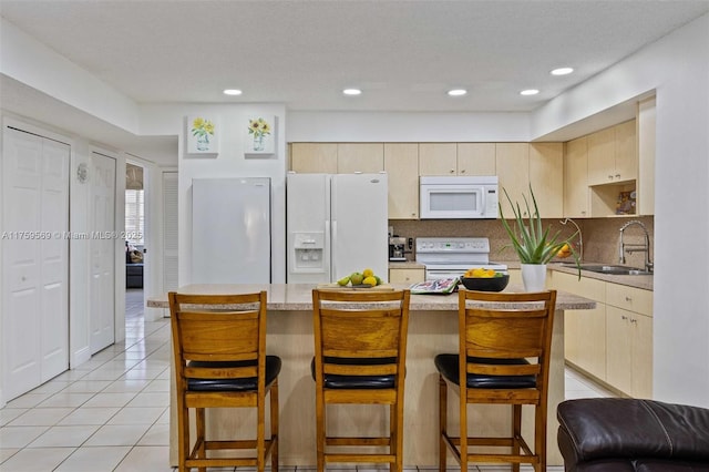 7801 SW 9th Ter, Miami, FL 33144 - kitchen with white appliances, a breakfast bar, light tile patterned floors, light countertops, and a sink