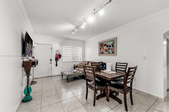 dining room with light tile patterned floors, ornamental molding, and track lighting