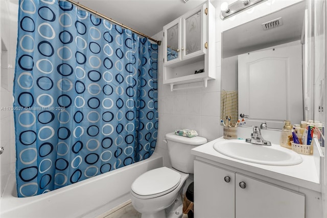 full bath with toilet, vanity, visible vents, tile walls, and shower / bath combo