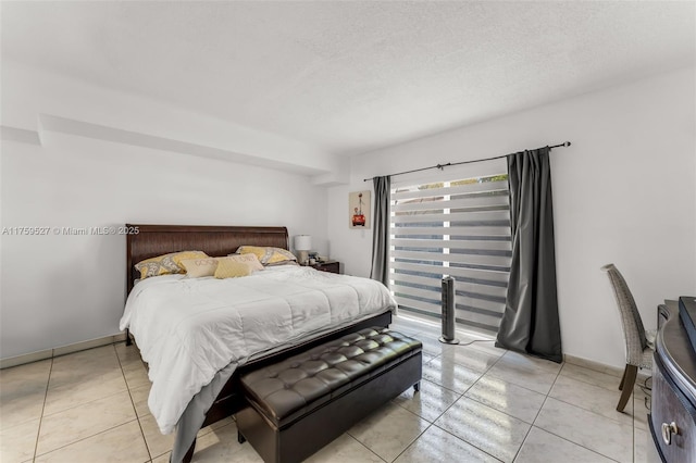 bedroom featuring light tile patterned floors, a textured ceiling, and baseboards