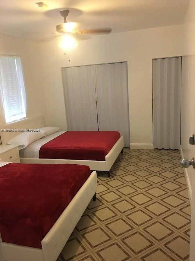 bedroom featuring a ceiling fan, light floors, and multiple closets